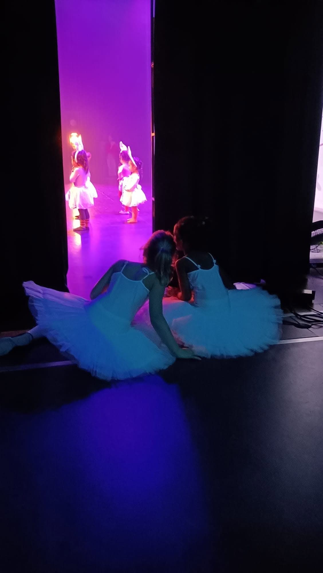 Jonge ballerina's in witte tutu's op het podium in paars licht