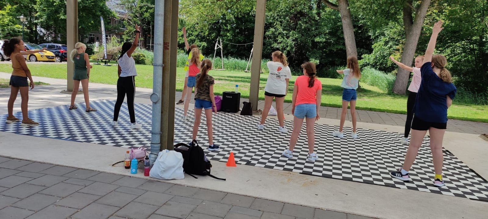 Kinderen dansen buiten op een geblokte dansvloer in het park