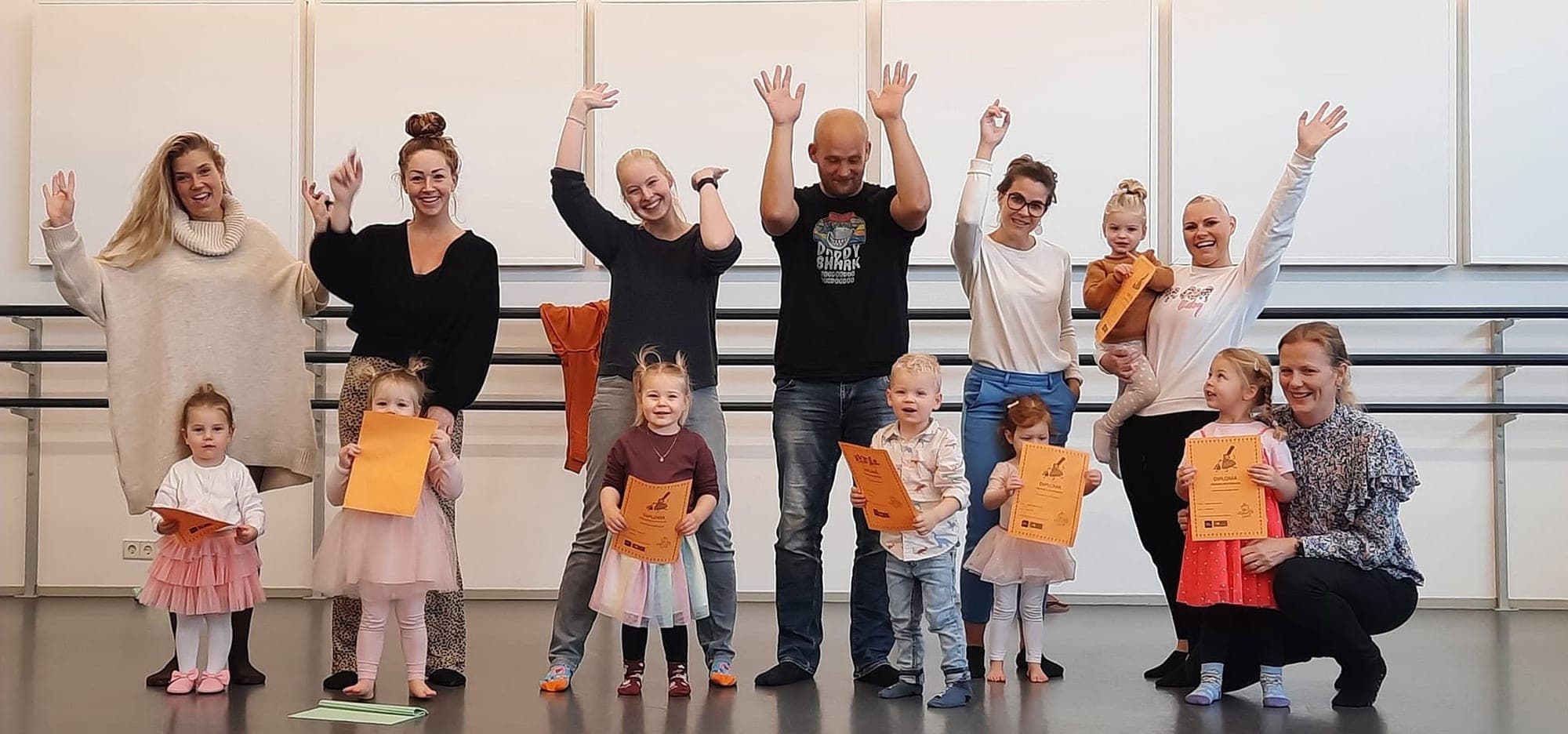 Dreumesen met hun ouders juichen met een diploma na de laatste dreumesdansles