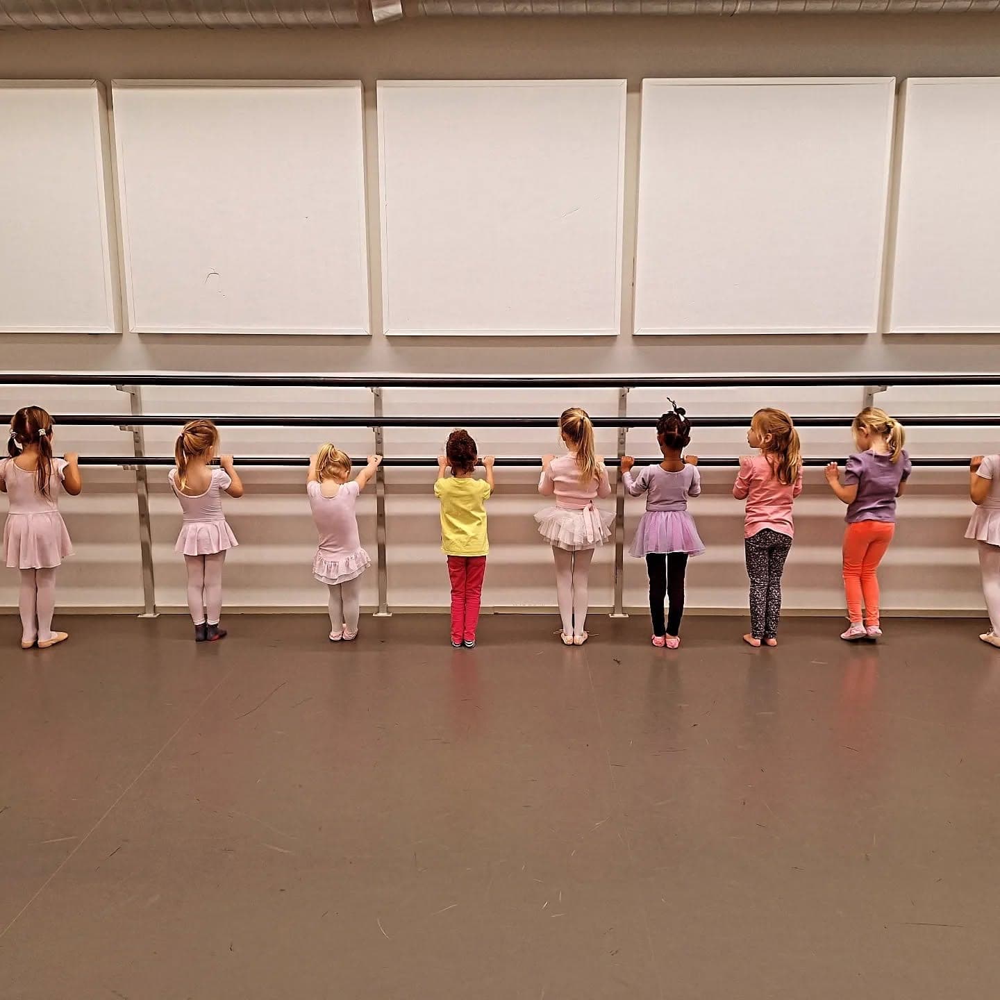 Rij peuters in balletpakjes aan de barre, van achteren gezien