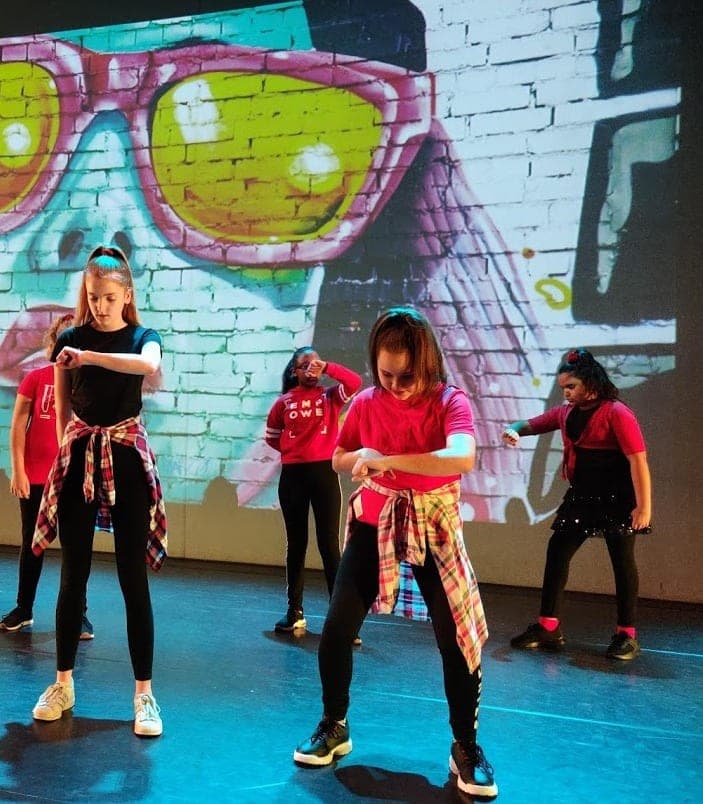 Kinderen dansen streetdance op het podium voor een graffitidecor